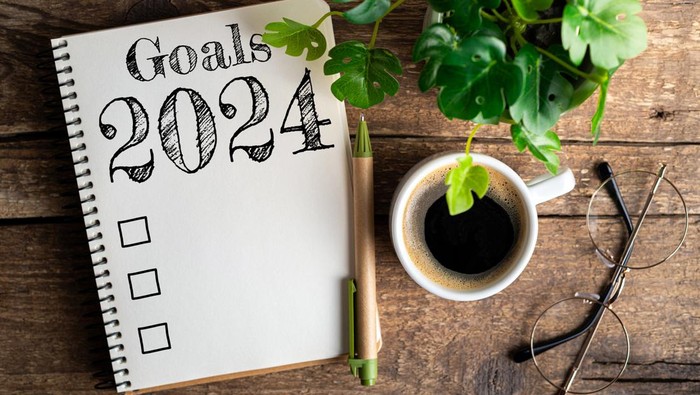 New year goals 2024 on desk. 2024 resolutions list with notebook, coffee cup on table. Goals, resolutions, plan, action, checklist concept. New Year 2024 template, copy space