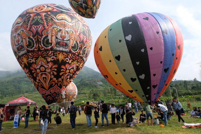 Sejumlah pengunjung menyaksikan penerbangan balon tradisional di Kahyangan Sky View kawasan lereng Bukit Seroja, Desa Maron, Garung Wonosobo, Jawa Tengah , Kamis (28/12/2023).  Penerbangan belasan balon tradisional berukuran besar di kawasan wisata alam Telaga Menjer tersebut sebagai atraksi wisata untuk menarik pengunjung saat musim libur Natal dan tahun baru 2024. ANTARA FOTO/Anis Efizudin/nym.