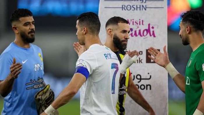 Nassrs Portuguese forward #07 Cristiano Ronaldo (C-left) and Ittihads French forward #09 Karim Benzema (C-right) greet players ahead of the Saudi Pro League football match between Al-Ittihad and Al-Nassr at King Abdullah Sports City Stadium in Jeddah on December 26, 2023. (Photo by AFP)