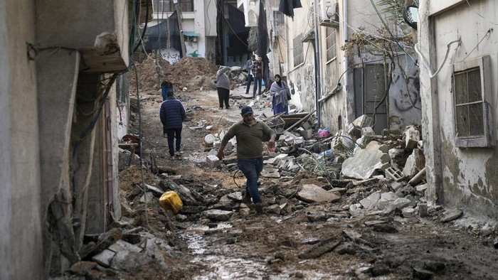 Palestinians walk through the aftermath of the Israeli military raid on Nur Shams refugee camp in the West Bank, Wednesday, Dec. 27, 2023. Israels forces raided a refugee camp in the northern occupied West Bank, killing at least six Palestinians, Palestinian health authorities said early Wednesday. (AP Photo/Majdi Mohammed)