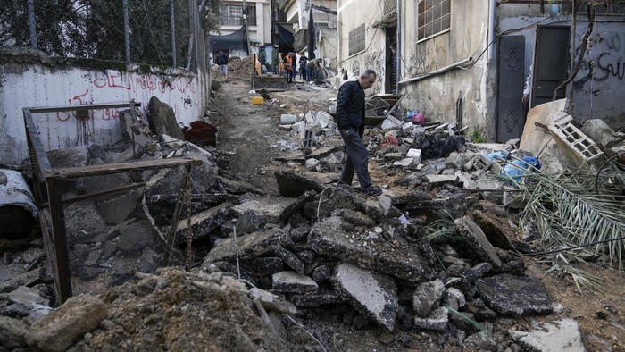 Palestinians walk through the aftermath of the Israeli military raid on Nur Shams refugee camp in the West Bank, Wednesday, Dec. 27, 2023. Israels forces raided a refugee camp in the northern occupied West Bank, killing at least six Palestinians, Palestinian health authorities said early Wednesday. (AP Photo/Majdi Mohammed)