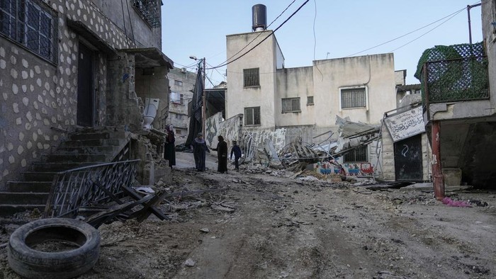 Kondisi Kamp Pengungsian di Tepi Barat Usai Dibombardir Israel Palestinians walk through the aftermath of the Israeli military raid on Nur Shams refugee camp in the West Bank, Wednesday, Dec. 27, 2023. Israel's forces raided a refugee camp in the northern occupied West Bank, killing at least six Palestinians, Palestinian health authorities said early Wednesday. (AP Photo/Majdi Mohammed)