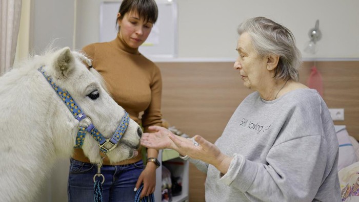 A patient strokes pony Dietrich led by volunteer Anastasia Kozyr at the Savyolovsky unit of a multi-profile palliative care centre in Moscow, Russia, December 14, 2023. Kozyr and her 23-year-old pony Dietrich have been visiting hospices for over a year, bringing some relief and spreading a little joy to patients who are in palliative care. REUTERS/Evgenia Novozhenina TPX IMAGES OF THE DAY