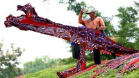 Pekerja melempar kain dari atas tanggul agar terbentang dan tersinari matahari.