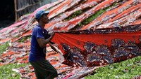 Pekerja menggulung kain setelah dijemur di bawah sinar matahari.