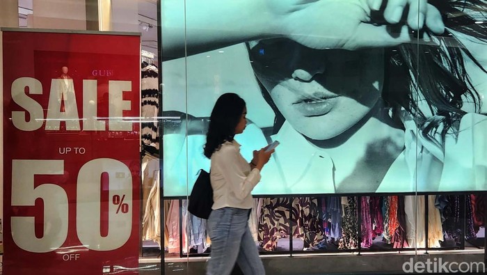 Pengunjung melintas di depan papan promosi potongan harga (diskon) di pusat perbelanjaan di Jakarta Selatan, Kamis (28/12/2023). Menjelang akhir tahun 2023 dan menyambut tahun baru 2024, pengunjung mall dimanjakan dengan berbagai potongan harga (diskon) hingga 70 persen.