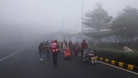 Orang-orang berjalan di tengah kabut tebal di Bandara Internasional Indira Gandhi di New Delhi, India. 