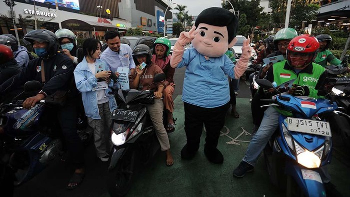Fanta First Voters bagian dari TKN Fanta HQ melakukan bagi-bagi susu dan bunga gratis kepada warga yang ada di kawasan Sarinah, Jakarta Pusat, Jumat (29/12/2023).