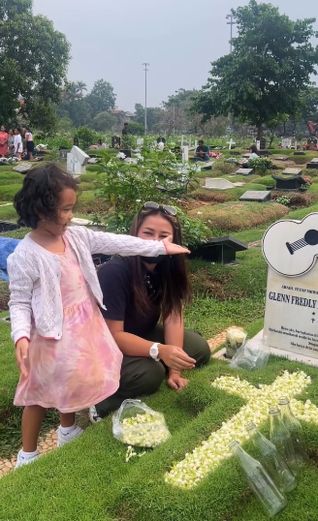 Gewa juga ikut memberikan bunga melati ke atas makam yang dibantu Mutia Ayu. Mutia Ayu terlihat mengenakan baju kasual berupa kaos hitam dan celana cargo. Foto: Instagram @mutia_ayuu