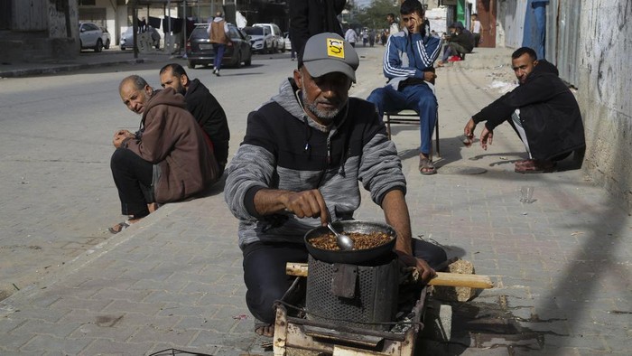 Krisis Gas, Warga Gaza Masak dengan Tungku dan Kayu Bakar A Palestinian cooks on a sidewalk during the ongoing Israeli bombardment of the Gaza Strip in Rafah on Sunday, Dec. 10, 2023. (AP Photo/Hatem Ali)