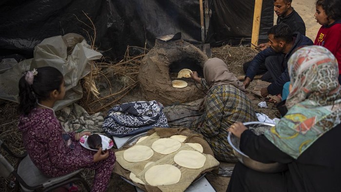 Palestinians displaced by the Israeli bombardment of the Gaza Strip cook at the makeshift tent camp in the Muwasi area on Thursday, Dec. 28, 2023. (AP Photo/Fatima Shbair)
