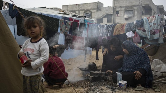 Krisis Gas, Warga Gaza Masak dengan Tungku dan Kayu Bakar Palestinians displaced by the Israeli bombardment of the Gaza Strip cook at the makeshift tent camp in the Muwasi area on Thursday, Dec. 28, 2023. (AP Photo/Fatima Shbair)