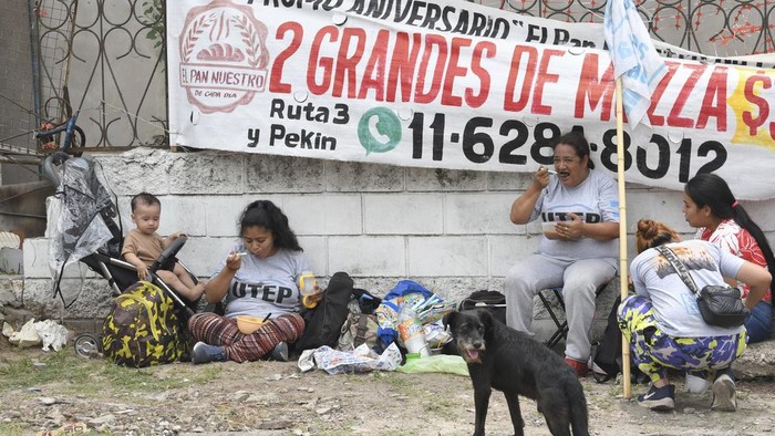 Demonstrators eat a free meal for those participating in a protest against the economic reforms of President Javier Milei in La Matanza, partially blocking a road on the outskirts of Buenos Aires, Argentina, Thursday, Dec. 28, 2023. (AP Photo/Gustavo Garello)