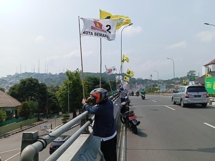 Petugas Bawaslu Kota Semarang mencopoti bendera parpol di flyover Jatingaleh, Semarang, Jumat (29/12/2023).
