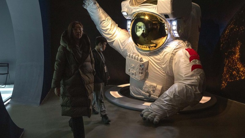A visitor stands near a display showing earth during an exhibition about China's space program in Beijing, Thursday, Dec. 28, 2023. China's burgeoning space program plans to place astronauts on the moon before 2030 and expand the country's orbiting space station against the background of a rivalry with the U.S. for reaching new milestones in outer space, reflecting their competition for influence on global events. (AP Photo/Ng Han Guan)