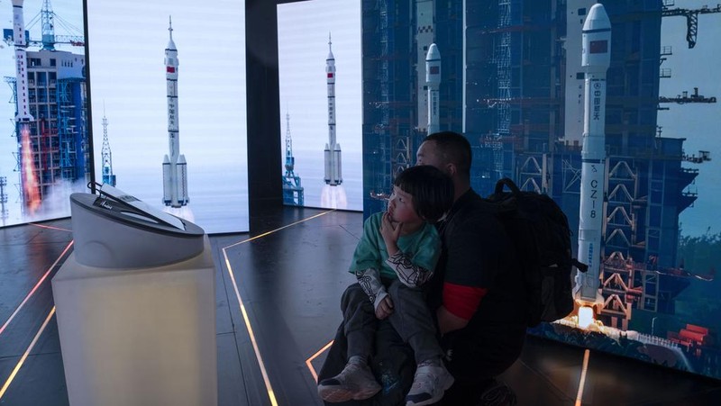 A visitor stands near a display showing earth during an exhibition about China's space program in Beijing, Thursday, Dec. 28, 2023. China's burgeoning space program plans to place astronauts on the moon before 2030 and expand the country's orbiting space station against the background of a rivalry with the U.S. for reaching new milestones in outer space, reflecting their competition for influence on global events. (AP Photo/Ng Han Guan)