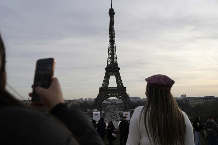 A board warns about a strike at the Eiffel Tower, Wednesday, Dec. 27, 2023 in Paris. The Eiffel Tower was shut down to visitors Wednesday because of a strike over contract negotiations, the day the Paris monument marks 100 years since the death of its creator, Gustave Eiffel. Tourists can still access the glass-enclosed esplanade beneath the tower, but access to the 300-meter (984-foot) landmark itself is closed until further notice, (AP Photo/Lewis Joly)