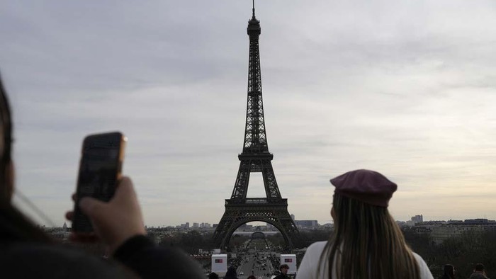 A board warns about a strike at the Eiffel Tower, Wednesday, Dec. 27, 2023 in Paris. The Eiffel Tower was shut down to visitors Wednesday because of a strike over contract negotiations, the day the Paris monument marks 100 years since the death of its creator, Gustave Eiffel. Tourists can still access the glass-enclosed esplanade beneath the tower, but access to the 300-meter (984-foot) landmark itself is closed until further notice, (AP Photo/Lewis Joly)