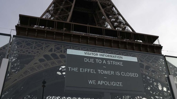 A board warns about a strike at the Eiffel Tower, Wednesday, Dec. 27, 2023 in Paris. The Eiffel Tower was shut down to visitors Wednesday because of a strike over contract negotiations, the day the Paris monument marks 100 years since the death of its creator, Gustave Eiffel. Tourists can still access the glass-enclosed esplanade beneath the tower, but access to the 300-meter (984-foot) landmark itself is closed until further notice, (AP Photo/Lewis Joly)