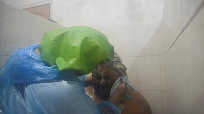 Relawan Gereja di Bolivia Mendandani Ratusan Tunawisma Saat Libur Nataru A volunteer bathes a homeless woman at an evangelical church where homeless people receive clothing, food and free showers during holidays, in La Paz, Bolivia December 28, 2023. REUTERS/Claudia Morales