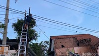 Petugas memperbaiki instalasi listrik yang putus akibat ledakan.