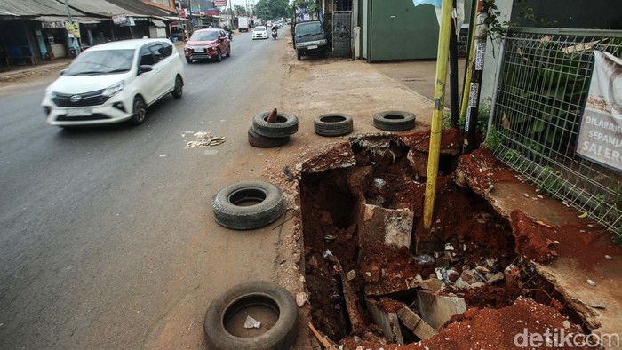 Kendaraan melintas di Jalan Raya Narogong, Bantargebang, Bekasi, Jumat (29/12/2023). Longsor yang terjadi pada Rabu (27/12/2023) malam membuat trotoar berlubang.