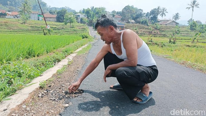 Warga memperlihatkan jalan yang mudah rusak.