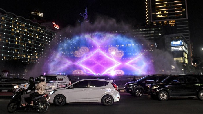 Petugas mengatur lalu lintas di dekat water screen yang sedang di uji coba untuk perayaan malam tahun baru di Bundaran HI, Jakarta, Sabtu (30/12/2023). Pemerintah Provinsi DKI Jakarta menggelar perayaan malam tahun baru 2024 di Bundaran HI pada Minggu (31/12), dengan menampilkan pertunjukan water screen, atraksi drone, dan video mapping. ANTARA FOTO/Hafidz Mubarak A/Spt.