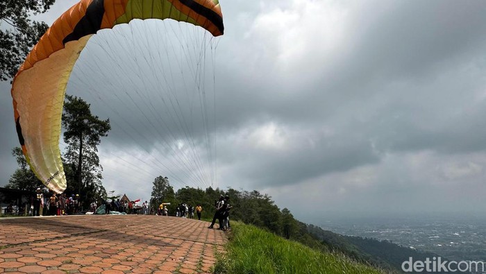 Wisatawan sedang melakukan paralayang di atas Gunung Banyak
