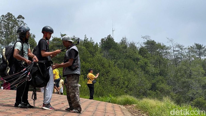 wisatawan sedang bersiap melakukan paralayang