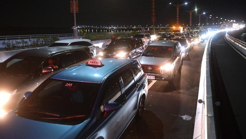 Calon penumpang pesawat berjalan di Jalan Tol Bali Mandara setelah mobil yang ditumpanginya terjebak kemacetan saat akan menuju ke Bandara Internasional I Gusti Ngurah Rai di Badung, Bali, Jumat (29/12/2023). Kemacetan itu terjadi sejak Jumat sore akibat padatnya kendaraan yang melintas di kawasan jalan akses Bandara I Gusti Ngurah Rai pada musim liburan akhir tahun. ANTARA FOTO/Fikri Yusuf/nym.
