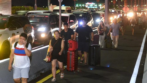 Calon penumpang pesawat berjalan di Jalan Tol Bali Mandara setelah mobil yang ditumpanginya terjebak kemacetan saat akan menuju ke Bandara Internasional I Gusti Ngurah Rai di Badung, Bali, Jumat (29/12/2023). Kemacetan itu terjadi sejak Jumat sore akibat padatnya kendaraan yang melintas di kawasan jalan akses Bandara I Gusti Ngurah Rai pada musim liburan akhir tahun. ANTARA FOTO/Fikri Yusuf/nym.