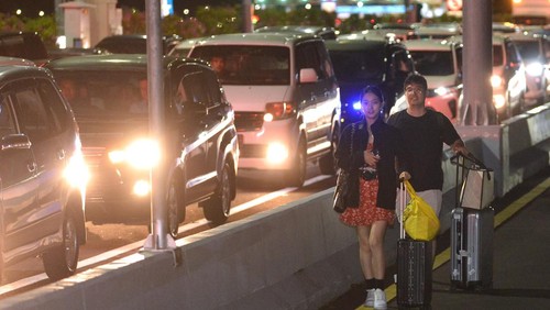 Calon penumpang pesawat berjalan di Jalan Tol Bali Mandara setelah mobil yang ditumpanginya terjebak kemacetan saat akan menuju ke Bandara Internasional I Gusti Ngurah Rai di Badung, Bali, Jumat (29/12/2023). Kemacetan itu terjadi sejak Jumat sore akibat padatnya kendaraan yang melintas di kawasan jalan akses Bandara I Gusti Ngurah Rai pada musim liburan akhir tahun. ANTARA FOTO/Fikri Yusuf/nym.