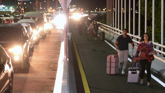 Potret Turis Jalan Kaki ke Bandara Ngurah Rai Imbas Lalin Bali Macet Parah Calon penumpang pesawat berjalan di Jalan Tol Bali Mandara setelah mobil yang ditumpanginya terjebak kemacetan saat akan menuju ke Bandara Internasional I Gusti Ngurah Rai di Badung, Bali, Jumat (29/12/2023). Kemacetan itu terjadi sejak Jumat sore akibat padatnya kendaraan yang melintas di kawasan jalan akses Bandara I Gusti Ngurah Rai pada musim liburan akhir tahun. ANTARA FOTO/Fikri Yusuf/nym.
