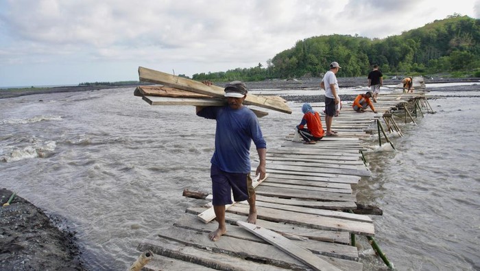Warga di Malang Gotong Royong Perbaiki Jembatan Kayu Sejumlah warga mengangkat kayu untuk dipasang di jembatan kayu yang rusak di daerah aliran sungai (DAS) Gunung Semeru, Desa Lebakharjo, Ampelgading, Malang, Jawa Timur, Sabtu (30/12/2023). Jembatan swadaya masyarakat sepanjang 100 meter yang digunakan sebagai jalan alternatif antar desa itu dapat memotong jarak tempuh hingga 14 kilometer, rusak akibat diterjang arus sungai setelah hujan. ANTARA FOTO/Irfan Sumanjaya/Spt.