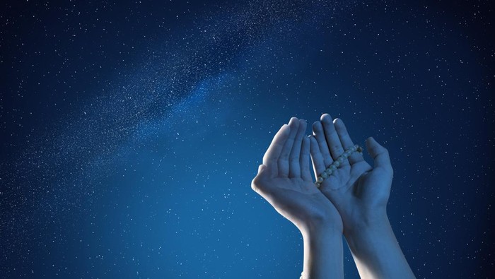 Muslim hands praying with prayer beads at outdoor with night scene background