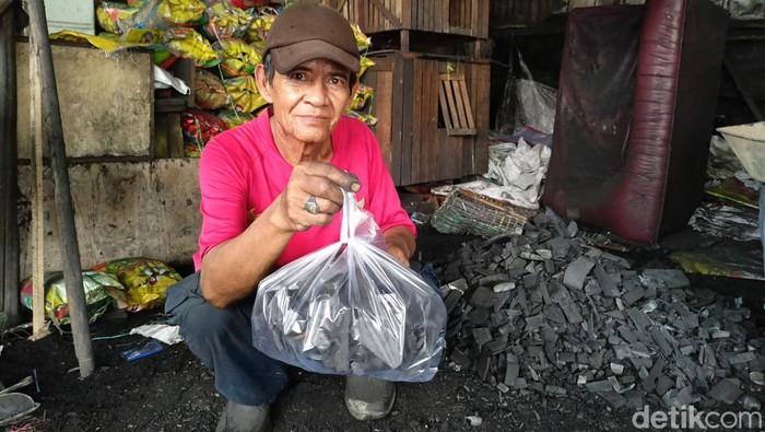 Pedagang arang di kawasan Jakabaring sedang mewadahi arang yang hendak dijual.