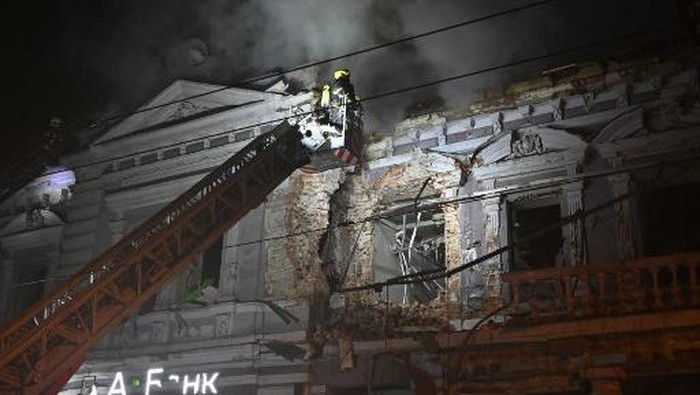 A firefighter on a crane combats a fire in a building after a Russian drone attack in Kharkiv on eraly December 31, 2023, amid the Russian invasion of Ukraine. (Photo by SERGEY BOBOK / AFP)