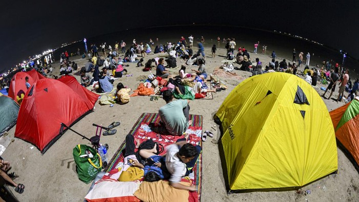 Sejumlah warga menunggu malam pergantian tahun di Pantai Lagoon, Taman Impian Jaya Ancol, Jakarta, Minggu (31/12/2023). Pantai di Ancol menjadi salah satu destinasi favorit warga Jakarta dan daerah-daerah lainnya untuk menghabiskan malam pergantian tahun dengan hiburan pertunjukan musik dan kembang api. ANTARA FOTO/Muhammad Adimaja/rwa.