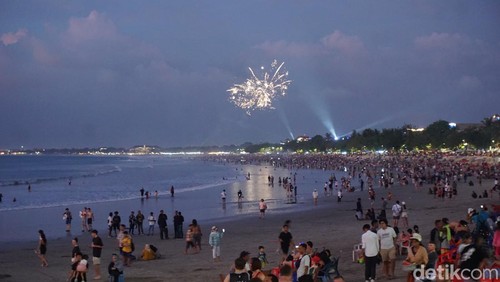 Sejumlah pengunjung Pantai Kuta, Bali menunggu pergantian tahun 2023-2024, Minggu (31/12/2023). (Agus Eka/detikBali)