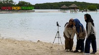 Tiga orang wisatawan asyik foto bersama di pinggir Pantai Pasir Perawan.