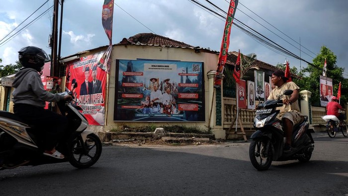 Kampung Ganjar Mahfud di Solo Warga melewati poster pasangan Capres dan Cawapres nomor urut 3 Ganjar Pranowo dan Mahfud MD yang dipajang di Kampung Ganjar Mahfud, Kelurahan Pajang, Kecamatan Laweyan, Solo, Jawa Tengah, Senin (1/1/2024). Kampung tersebut diresmikan untuk sosialisasi program kerja pasangan Capres dan Cawapres nomor urut 3 Ganjar Pranowo dan Mahfud MD guna memenangkan Pemilu Presiden pada Februari 2024 mendatang. ANTARAFOTO/Maulana Surya/foc.