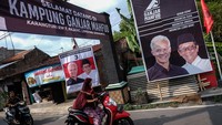 Warga melintas di depan poster Ganjar Pranowo dan Mahfud Md yang dipajang di Kelurahan Pajang, Kecamatan Laweyan, Solo, Jawa Tengah, Senin (1/1/2024).
