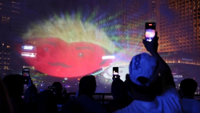 People use their mobile phones as they watch a video mapping show at the Bundaran Hotel Indonesia roundabout while celebrating New Years Eve in Jakarta, Indonesia, December 31, 2023. REUTERS/Ajeng Dinar Ulfiana