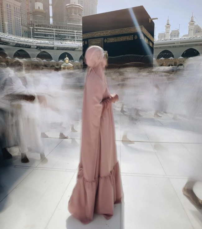 Berpose di depan Kabah, BCL terlihat memilih gamis dengan model puffy pada bagian bawah bernuansa merah muda. Tentu dipadupadankan dengan khimar yang syar’i dan kekinian. Foto: Instagram @itsmebcl