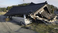 Mobil itu tertimpa bangunan rumah karena tak sempat dievakuasi oleh pemiliknya. Kyodo vs AP.  