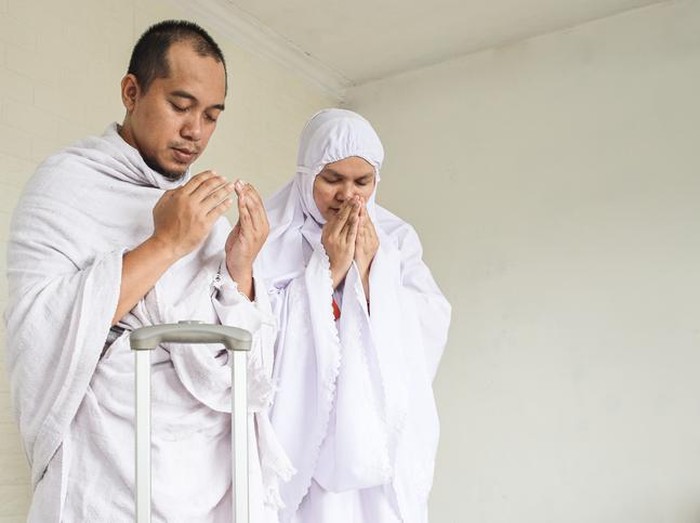 Indonesian couple praying dua before hajj and umrah, leaving home.