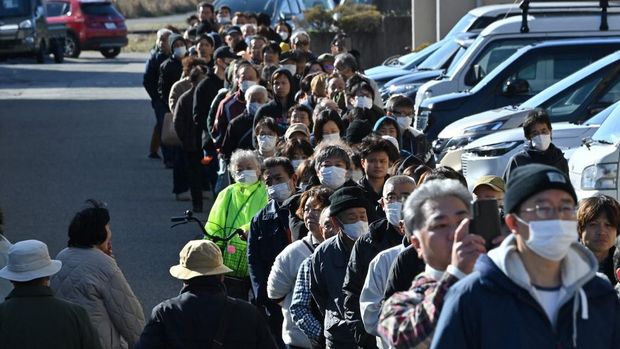 Orang-orang mengantri di sekitar balai Kota Shika saat mereka menunggu untuk menerima air di titik distribusi di Shika, prefektur Ishikawa pada 2 Januari 2024, sehari setelah gempa besar berkekuatan 7,5 skala Richter melanda wilayah Noto di prefektur Ishikawa. Tim penyelamat Jepang berjuang melawan waktu dan gempa susulan yang kuat pada tanggal 2 Januari untuk menemukan korban selamat dari gempa besar yang melanda pada Hari Tahun Baru, yang menewaskan sedikitnya enam orang dan meninggalkan jejak kehancuran. (Photo by Kazuhiro NOGI / AFP)