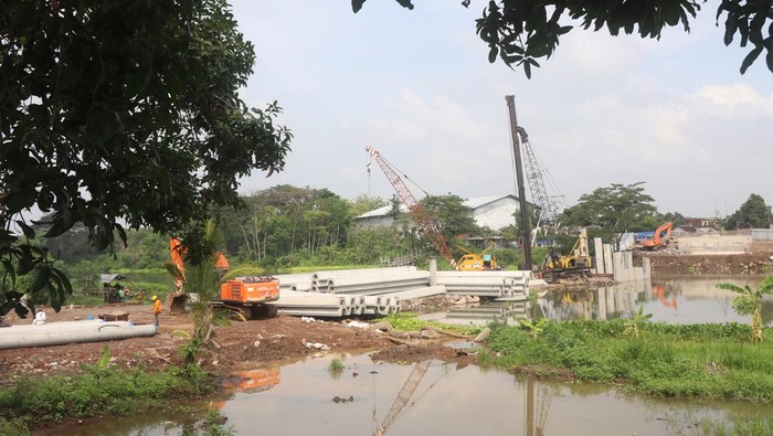 Warga menggunakan perahu penyeberangan dengan latar belakang proyek pembangunan Jembatan Jongbiru di Sungai Brantas, Kediri, Jawa Timur, Rabu (3/1/2024). Proyek pembangunan jembatan sepanjang 133 meter sebagai penghubung kota dengan kabupaten Kediri sekaligus jalur penyangga menuju Bandara Dhoho Kediri tersebut ditargetkan selesai pada Mei 2024. ANTARA FOTO/Prasetia Fauzani/rwa.