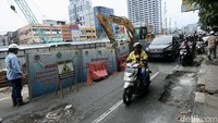 Tampak jalan yang ambles dihalangi dengan pembatas seng bertuliskan Mohon maaf perjalanan anda terganggu pekerjaan relokasi SKTT 150 kV Mangga Besar-Ketapang yang terdampak MRT.